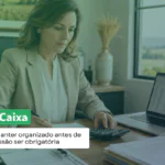 Contadora analisa documentos e usa uma calculadora ao lado do notebook, em escritório com vista para o campo. Texto: “Livro Caixa: por que manter organizado antes de a transmissão ser obrigatória”.