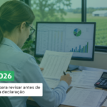 Mulher contadora, de costas, analisa documentos em frente ao computador, em um escritório com vista para uma área rural. Sobre a imagem, aparece o texto: “ITR 2026: 5 pontos para revisar antes de entregar a declaração”.